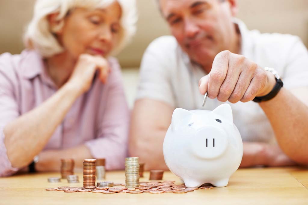 couple adding coins to piggy bank
